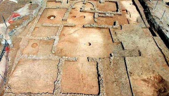 Aerial view of an archaeological site featuring stone foundations and layout of ancient structures. - Olive Oil Times
