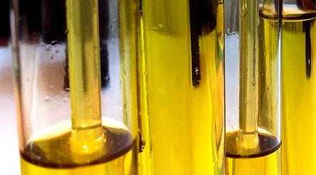 Test tubes containing olive oil samples arranged in a laboratory setting. - Olive Oil Times