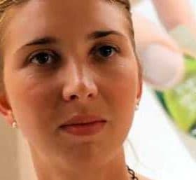 Close-up portrait of a woman with light hair and earrings, looking directly at the camera. - Olive Oil Times
