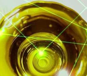 Close-up view of olive oil in a circular container with laser light effects overlaying the surface. - Olive Oil Times
