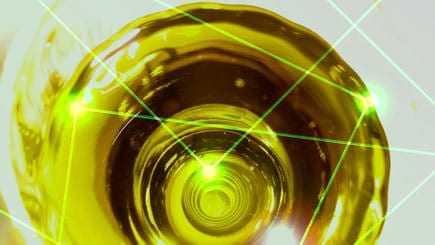 Close-up view of olive oil in a circular container with laser light effects overlaying the surface. - Olive Oil Times