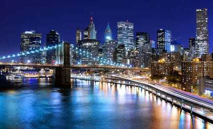 Night view of the Brooklyn Bridge with the Manhattan skyline illuminated in the background. - Olive Oil Times