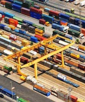 Aerial view of a cargo container terminal with various shipping containers and cranes. - Olive Oil Times