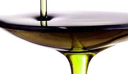 Olive oil being poured into a shallow bowl, showcasing its rich color and texture. - Olive Oil Times