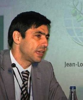 Jean-Louis Barjol speaking at a conference with a logo in the background. - Olive Oil Times
