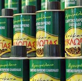Row of green cans of Kyklopas extra virgin olive oil with yellow labels and Greek text. - Olive Oil Times