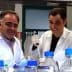 Two male scientists wearing lab coats and gloves working with laboratory equipment and bottles. - Olive Oil Times