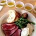 A plate featuring sliced roast beef, bread, and small cups of olive oil arranged on a table. - Olive Oil Times