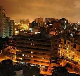 A nighttime view of Lima, Peru, showcasing buildings and city lights under a cloudy sky. - Olive Oil Times