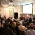 A panel discussion taking place with a seated audience in a well-lit room. - Olive Oil Times