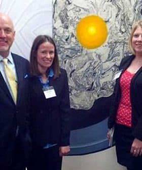 Five individuals standing together in front of a large circular artwork featuring a yellow center. - Olive Oil Times
