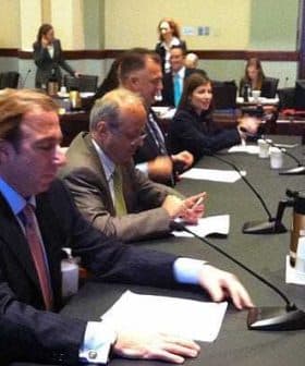 A group of individuals seated at a conference table during a meeting in a formal setting. - Olive Oil Times