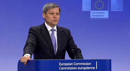 Man speaking at a podium during a European Commission press conference with a blue background. - Olive Oil Times