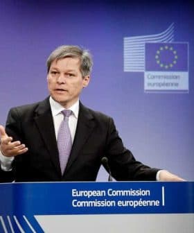 A man speaking at a podium during a European Commission press conference with the EU emblem in the background. - Olive Oil Times