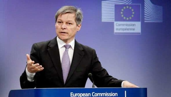 A man speaking at a podium during a European Commission press conference with the EU emblem in the background. - Olive Oil Times