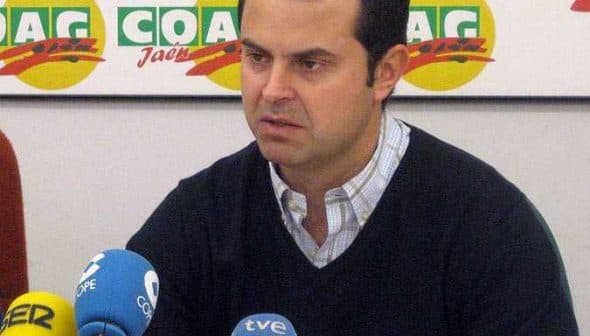 A man speaking at a press conference with multiple microphones in front of him. - Olive Oil Times