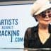 Yoko Ono wearing a white hat and sunglasses speaking at a podium with a sign for Artists Against Fracking. - Olive Oil Times