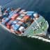 Aerial view of a cargo ship loaded with colorful shipping containers on water. - Olive Oil Times