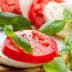 Sliced tomatoes and mozzarella cheese garnished with fresh basil leaves on a plate. - Olive Oil Times