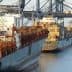 Two cargo ships docked at a port with containers stacked on their decks. - Olive Oil Times
