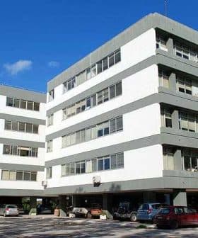 A multi-story office building featuring a modern architectural design with large windows and a gray and white color scheme. - Olive Oil Times