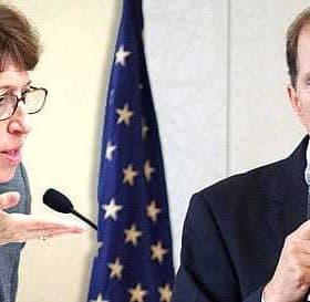 Two individuals in a discussion, one speaking into a microphone and the other gesturing with their hand. - Olive Oil Times