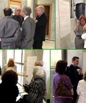 A group of people engaged in discussion during an international meeting, with papers and notes visible. - Olive Oil Times