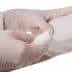 A medical professional in gloves applying a bandage to a patient's arm. - Olive Oil Times