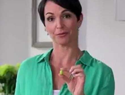Woman with short dark hair holding a small green object in her hand while wearing a green shirt. - Olive Oil Times