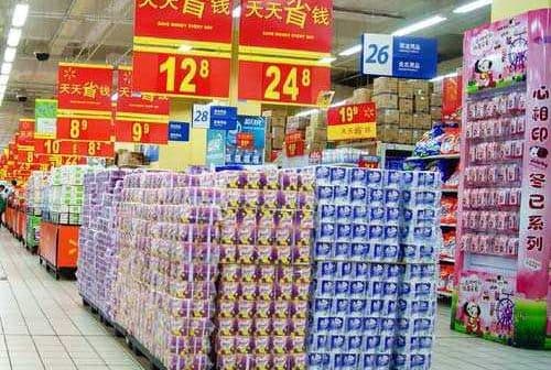 Supermarket aisle featuring stacked product displays and promotional signage in Chinese. - Olive Oil Times