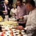 Chef pouring olive oil over a plate of food at a culinary event with attendees observing. - Olive Oil Times