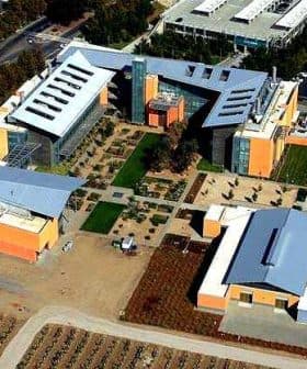 Aerial view of a modern building complex with landscaped gardens and multiple structures. - Olive Oil Times