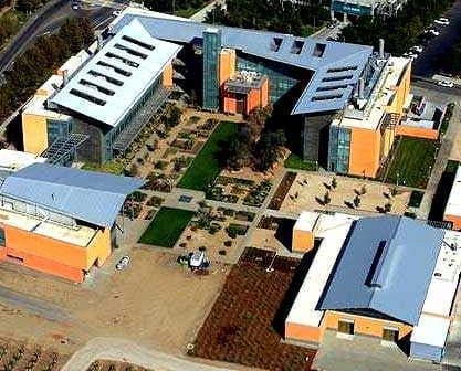 Aerial view of a modern building complex with landscaped gardens and multiple structures. - Olive Oil Times