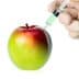 A red and green apple being injected with a syringe containing a green liquid. - Olive Oil Times