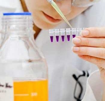 Laboratory technician using a pipette to transfer liquid into multiple test tubes in a lab setting. - Olive Oil Times