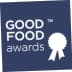 Logo of the Good Food Awards featuring a ribbon and text on a blue background. - Olive Oil Times