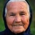 Elderly woman with a warm smile, wearing a dark headscarf and showing facial wrinkles. - Olive Oil Times