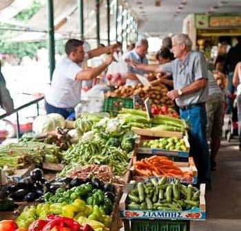 A market stall displaying a variety of fresh vegetables including peppers, cucumbers, and carrots. - Olive Oil Times