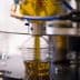 Machine filling a plastic bottle with olive oil during the bottling process. - Olive Oil Times