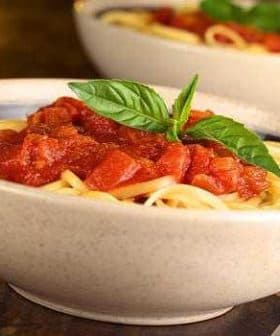 Bowl of spaghetti topped with tomato sauce and fresh basil leaves. - Olive Oil Times