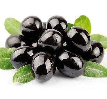 A cluster of black olives resting on green leaves, showcasing their glossy surface. - Olive Oil Times