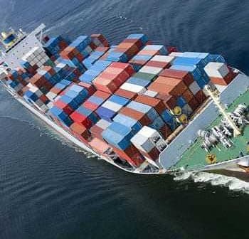 Cargo ship with multiple stacked shipping containers navigating through water. - Olive Oil Times