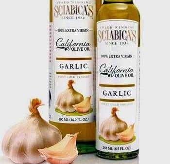 Two bottles of garlic olive oil with a garlic bulb in front on a neutral background. - Olive Oil Times