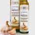 Two bottles of garlic olive oil with a garlic bulb in front on a neutral background. - Olive Oil Times