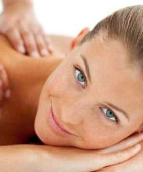 A woman with blue eyes and light brown hair lying on a massage table during a massage session. - Olive Oil Times