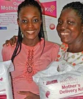 Two women smiling while holding Mother's Delivery Kits in their hands. - Olive Oil Times