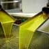 Freshly extracted olive oil flowing from a processing machine into a container. - Olive Oil Times