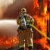 Firefighter in protective gear using a hose to spray water on a large fire. - Olive Oil Times