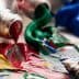 Opened paint tubes with red, green, blue, and yellow paint squeezed out onto a surface. - Olive Oil Times