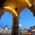Archway with decorative columns and lanterns, overlooking a city square in Trieste during twilight. - Olive Oil Times